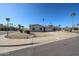 Tan single-story home featuring a two-car garage and low-maintenance desert landscaping at the corner of a cul-de-sac at 10720 E Sahuaro Dr, Scottsdale, AZ 85259