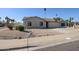 Tan single-story home featuring a two-car garage and low-maintenance desert landscaping near the sidewalk at 10720 E Sahuaro Dr, Scottsdale, AZ 85259