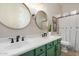 Well-lit bathroom featuring double sinks with green cabinets and round mirrors at 11307 E Ellis St, Mesa, AZ 85207