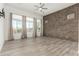 Bright living room with a brick wall, three windows, and wood-style flooring at 1143 N Quinn --, Mesa, AZ 85205