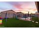 Beautiful backyard at dusk, with pool, patio, playground, and artificial turf at 11843 W Cambridge Ave, Avondale, AZ 85392