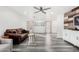 Spacious living room showcasing gray wood floors, a ceiling fan, and large windows for abundant natural light at 11843 W Cambridge Ave, Avondale, AZ 85392