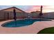 Inviting pool with a baja shelf, basketball hoop, and serene sunset views, perfect for outdoor relaxation at 11843 W Cambridge Ave, Avondale, AZ 85392