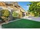 Landscaped backyard featuring a synthetic grass area, brick-paver patio, and mature trees at 123 W Sweet Shrub Ave, San Tan Valley, AZ 85140