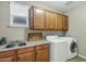 Well-lit laundry room featuring a stainless steel sink, wooden cabinets, and a modern washer and dryer at 123 W Sweet Shrub Ave, San Tan Valley, AZ 85140