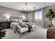 Modern bedroom with a chandelier, stylish furniture, and soft, neutral tones, creating a relaxing and inviting atmosphere at 12551 W Parkway Ln, Avondale, AZ 85323