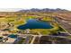 Stunning aerial view of a community pond surrounded by lush green spaces and covered ramadas at 12647 W Parkway Ln, Avondale, AZ 85323