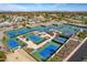 Aerial view of multiple blue tennis courts surrounded by lush greenery, close to the lake and the golf course at 13404 W Copperstone Dr, Sun City West, AZ 85375