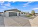 Charming single-story home with a large driveway, two-car garage, and arched doorway at 16239 N 47Th Dr, Glendale, AZ 85306