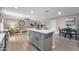 Bright kitchen island with quartz countertops and grey cabinetry adjacent to living and dining areas at 16239 N 47Th Dr, Glendale, AZ 85306