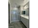 Bathroom featuring tiled shower with glass door, double sink vanity, and wood-look flooring at 17916 W Puget Ave, Waddell, AZ 85355