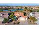 Aerial view of a tile roofed home with a three-car garage, desert landscaping, and community lake views at 21500 N 262Nd Ln, Buckeye, AZ 85396