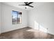 A bright and empty bedroom features hard wood floors, modern ceiling fan, and a large window at 2305 S Orange --, Mesa, AZ 85210