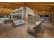 Outdoor lounge featuring plush seating around a stone fireplace, ceiling fans, and vaulted wood beam ceiling at 25135 N 177Th Dr, Surprise, AZ 85387