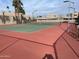 Outdoor tennis court with a red and green surface, surrounded by palm trees and community buildings at 4107 E Charter Oak N Rd, Phoenix, AZ 85032