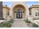 Elegant arched entryway with wrought iron double doors and manicured landscaping at 5827 E Sanna St, Paradise Valley, AZ 85253