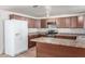 Kitchen with neutral countertops, brown cabinetry, white refrigerator, and gas range at 5952 W Coronado Rd, Phoenix, AZ 85035