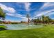 Scenic community pond featuring a fountain, lush green lawn, and mature trees on a sunny day at 628 Leisure World --, Mesa, AZ 85206