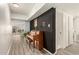 Inviting hallway features plank flooring, piano, black accent wall and access to other rooms at 7006 N 14Th Ave, Phoenix, AZ 85021