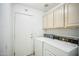 Well-lit laundry room equipped with classic appliances and overhead cabinets for storage at 7557 W Colter St, Glendale, AZ 85303