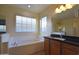 A large garden tub in a bathroom with dual sinks and dark countertops at 8776 W Peppertree Ln, Glendale, AZ 85305