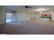 Bright living room with sliding glass doors, tile floors, carpeted area, and adjoining modern kitchen at 8776 W Peppertree Ln, Glendale, AZ 85305