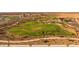 Aerial view of a park featuring a large grassy area with a walking path, landscaping, and a community lake at 10233 S Bickwell Trl, Apache Junction, AZ 85120