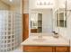 Bathroom features a glass block shower, neutral countertop vanity, and a large mirror providing a sleek design at 11258 E Ocaso Ave, Mesa, AZ 85212