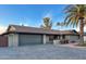 Home exterior showcasing a three-car garage, desert landscaping, and lush palm trees at 12426 W Cougar Dr, Sun City West, AZ 85375