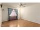 Cozy bedroom with a ceiling fan, wood floors, and large window with blue drapes at 12630 W Crystal Lake Dr, Sun City West, AZ 85375