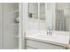 A bathroom featuring a pristine white vanity, with open shelving, a large mirror, and a shower with patterned curtains at 1325 S 239Th Dr, Buckeye, AZ 85326