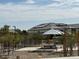 Community outdoor seating area with ramada, trees, desert landscaping, and a view of modern homes at 1325 S 239Th Dr, Buckeye, AZ 85326