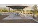 A covered picnic area with tables and benches, featuring barbecue facilities and shade in a well-maintained park at 1325 S 239Th Dr, Buckeye, AZ 85326