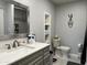 Modern bathroom featuring gray vanity with stylish sink, mirror, and open shelving for ample storage space at 13808 N 108Th Dr, Sun City, AZ 85351