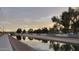 Picturesque view of a canal reflecting the sky, bordered by lush trees and walking paths at 1438 S 30Th St, Mesa, AZ 85204