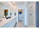 Bright bathroom featuring dual sinks, white cabinets, tile floors, and walk-in shower with white tiling at 14925 W Hackamore Dr, Surprise, AZ 85387