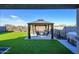 A covered gazebo, table, and chairs adorn this backyard with artificial grass, perfect for entertaining at 17618 W Paraiso Dr, Surprise, AZ 85387