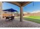 Covered back patio with stone pavers, an outdoor dining set, and a view of the landscaped yard at 19242 W Madison St, Buckeye, AZ 85326