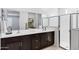 Bathroom featuring dual sinks, dark cabinets, a large mirror, and a glass-enclosed shower for a spa-like experience at 20670 N Confetti Ct, Maricopa, AZ 85138