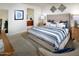 Relaxing bedroom with a plush bed, soft carpet, and an ensuite bathroom view through the hallway at 20670 N Confetti Ct, Maricopa, AZ 85138