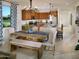 Cozy dining area with a wooden table, upholstered chairs, bench seating, and stylish light fixture, adjacent to kitchen at 20670 N Confetti Ct, Maricopa, AZ 85138