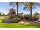 Elegant entrance to a neighborhood featuring manicured landscaping and mature palm trees at 20670 N Confetti Ct, Maricopa, AZ 85138