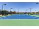 Full tennis court featuring a green and blue surface, benches, surrounding fence and lighting at 20670 N Confetti Ct, Maricopa, AZ 85138