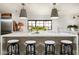 Spacious kitchen island with white marble countertops, seating, and designer pendant lights at 22619 N La Senda Dr, Scottsdale, AZ 85255