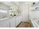 Bright bathroom showcasing double sinks with white cabinets and a large mirror and decorative floating shelves at 22924 E Desert Spoon Dr, Queen Creek, AZ 85142