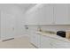 Laundry room featuring white cabinets, gold fixtures, and stylish patterned tile floor at 253 W Malibu Dr, Chandler, AZ 85248