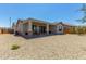 The backyard features gravel landscaping, a covered patio, and neutral exterior of the home at 27366 W Escuda Dr, Buckeye, AZ 85396