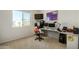 Bright bedroom featuring a corner desk, modern monitors, and a sunlit window with neighborhood views at 27366 W Escuda Dr, Buckeye, AZ 85396