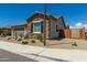 Home's exterior with stone accents, desert landscaping, a two-car garage, and privacy gate at 27366 W Escuda Dr, Buckeye, AZ 85396