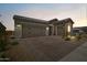 Charming home featuring a two-car garage, stone accents, landscaped yard, and a paved driveway at 27366 W Escuda Dr, Buckeye, AZ 85396